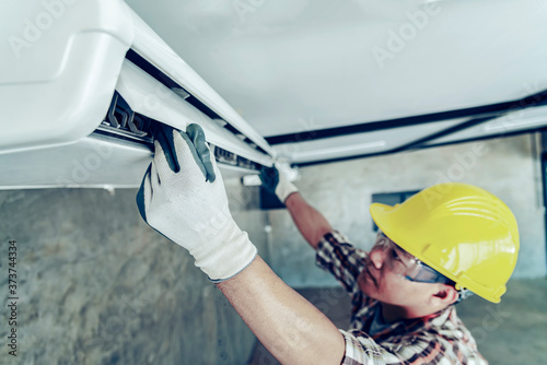 Male technician cleaning air conditioner indoors photo