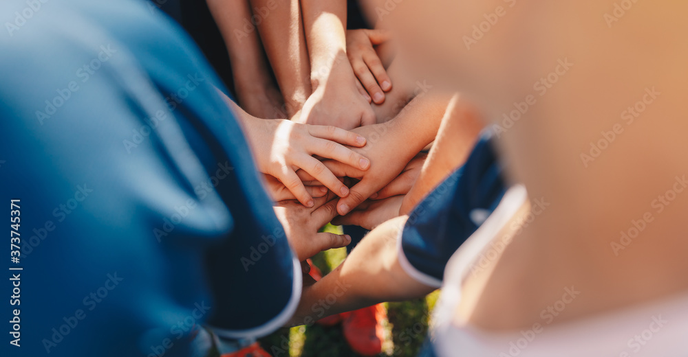 Kids sports team stacking hands before the game. Children school sports team. Boys team spirit. Kids motivating each other before the final soccer match