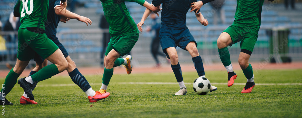 Footballers in action on the tournament game. Soccer football players competing for ball and kick ball during match in the stadium. Adult football competition Footballers in action on the tournament game. Soccer football players competing for ball and kick ball during match in the stadium. Adult football competition