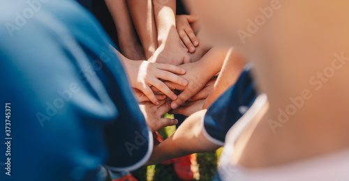Kids sports team stacking hands before the game. Children school sports team. Boys team spirit. Kids motivating each other before the final soccer match photo