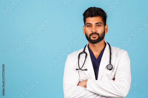 Handsome modern Indian / Asian doctor with stethoscope, in uniform on blue background