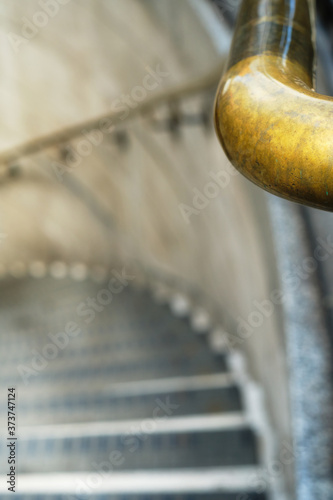 Perspective view of spiral stairs with gold handrail.