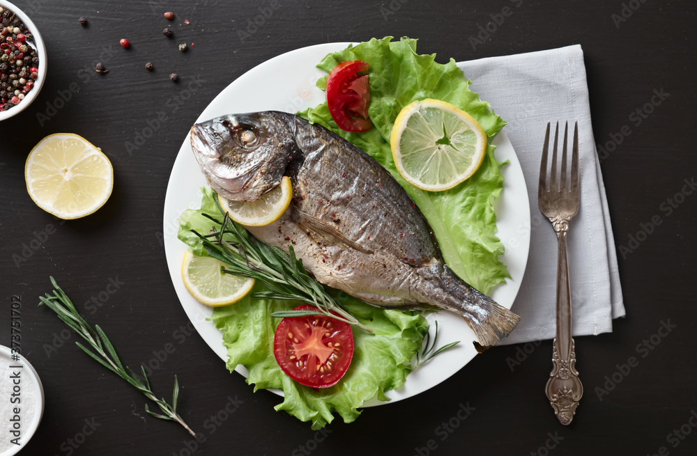 Baked dorado with vegetables, lemon, pepper, rosemary and lettuce. View from above. Baked dorado with vegetables, lemon, pepper, rosemary and lettuce. View from above.
