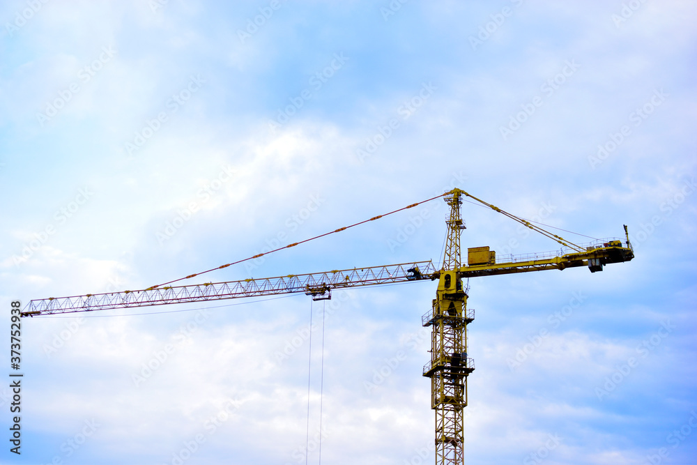 Tower construction crane on the background of the blue sky and the city Tower construction crane on the background of the blue sky and the city