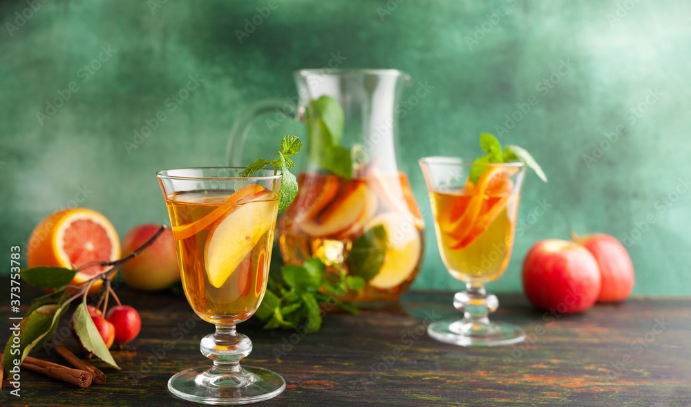 Apple cider cocktail with red oranges and spices in glasses and jug on table. Concept of autumn and winter drinks.