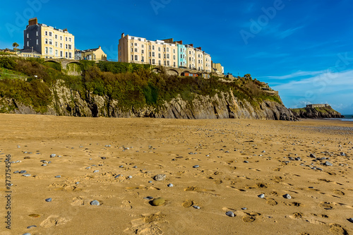 A view of sand and pebbles on the South Beach looking towards the cliffs and the colourful hotels above in Tenby, Pembrokeshire on a sunny day photo