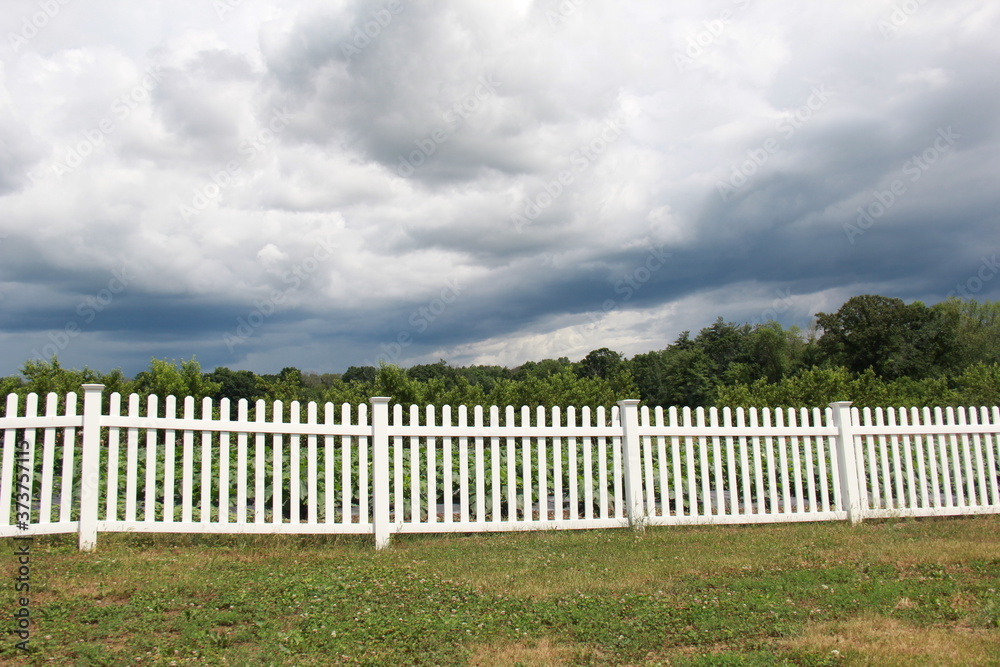 Summer storm over white picket fence