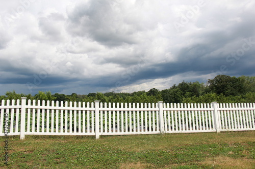 Summer storm over white picket fence