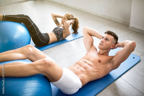 couple training abdominal muscle in gym room