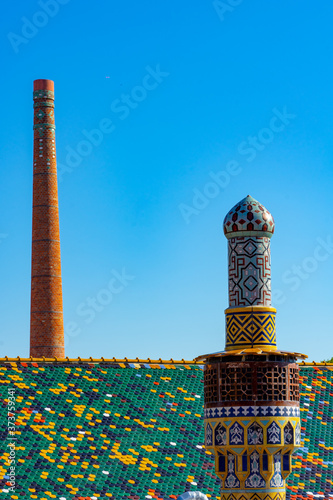 Pecs, Hungary - 21.08.2020: Beautiful colorful buildings in the famous Zsolnay quarter in Pécs with statue and decorated chimneys photo