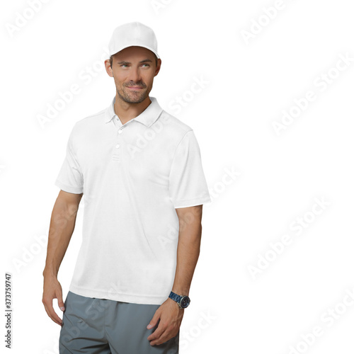 A handsome man stands on a white background, looking to the right with a smirk. He is wearing a white baseball cap, a white polo shirt, and gray shorts, looking to his left.