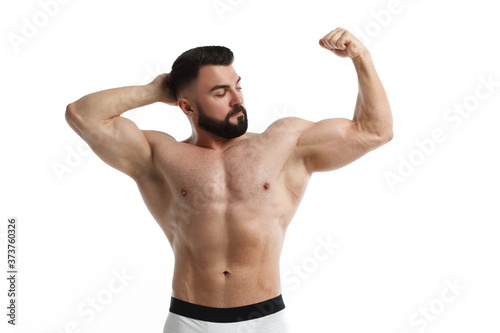 Athletic bearded man with a naked muscular torso holds one hand behind his head, the other demonstrates muscles, isolated on a white background.