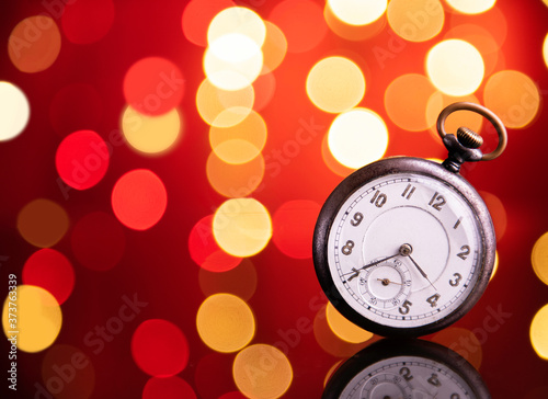 Old clock on set with blurry lite background with mirrored reflections in foreground 