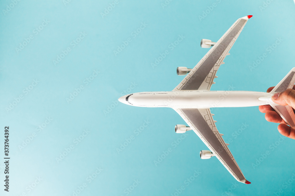 man's hand holding white airplane model over the turquoise background man's hand holding white airplane model over the turquoise background