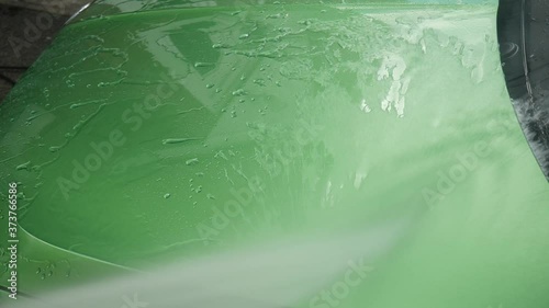 Rinsing green car bonnet with pressure washer photo