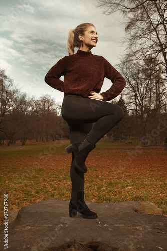 Nice lady posing in autumn park and exercising with steel hoop photo