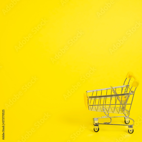 ?mall shopping cart on yellow background. Buy food concept. Text space