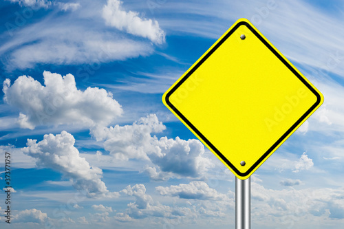 A warning road sign without an inscription on a blue sky background. Yellow warning road sign without text or drawing. Place for text. Your text on the road sign.