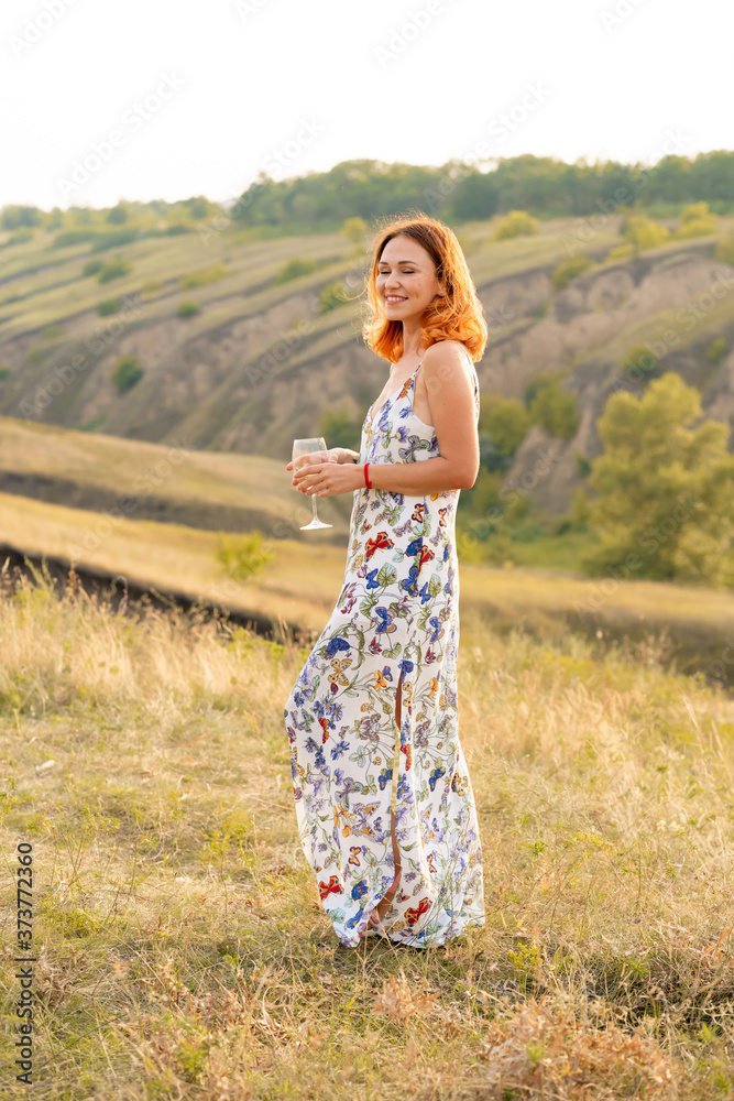 Beautiful red-haired girl is having fun and dancing in a field at sunset Beautiful red-haired girl is having fun and dancing in a field at sunset