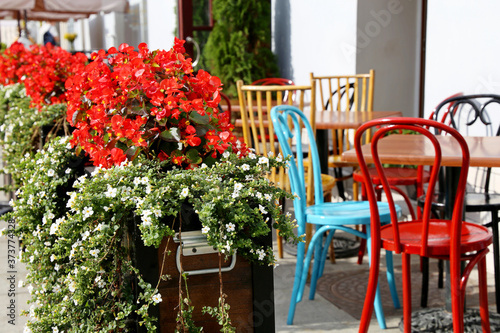 Street cafe in a city, tables and vintage metal chairs in a restaurant outdoor. Pots with flowers, elegant setting for celebration and date