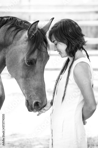 Black and white image of a girl looking after and stroking an Arabian breed horse.