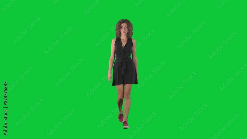 Serious displeased young woman walking and looking at camera on green screen chroma key background. 