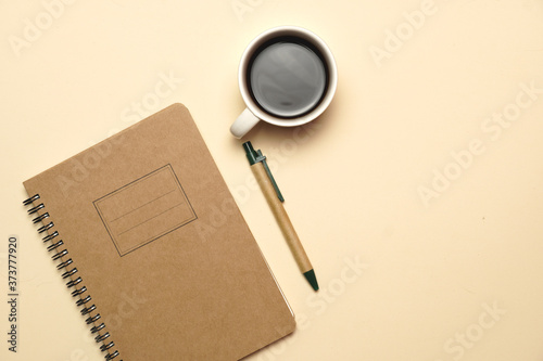 workspace with coffee notebook and pen on a pale orange background. flat lay.