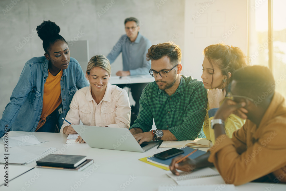 Group of college students using laptop in the classroom.