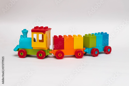 Children's plastic constructor steam locomotive. Train with carriages with cubes of all colors of the rainbow on a white background. Early learning. Educational toys