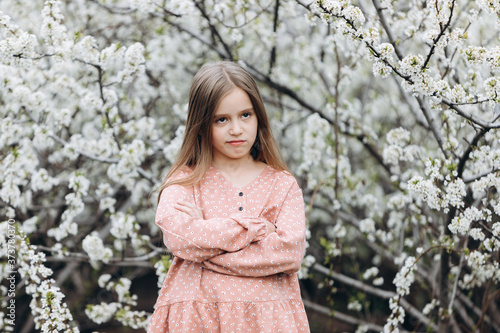 Foto A little child girl stands with her arms folded on her chest and looks with a satisfied expression on her face