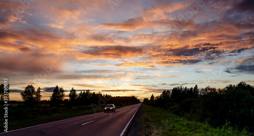 A single car on the road during sunset.