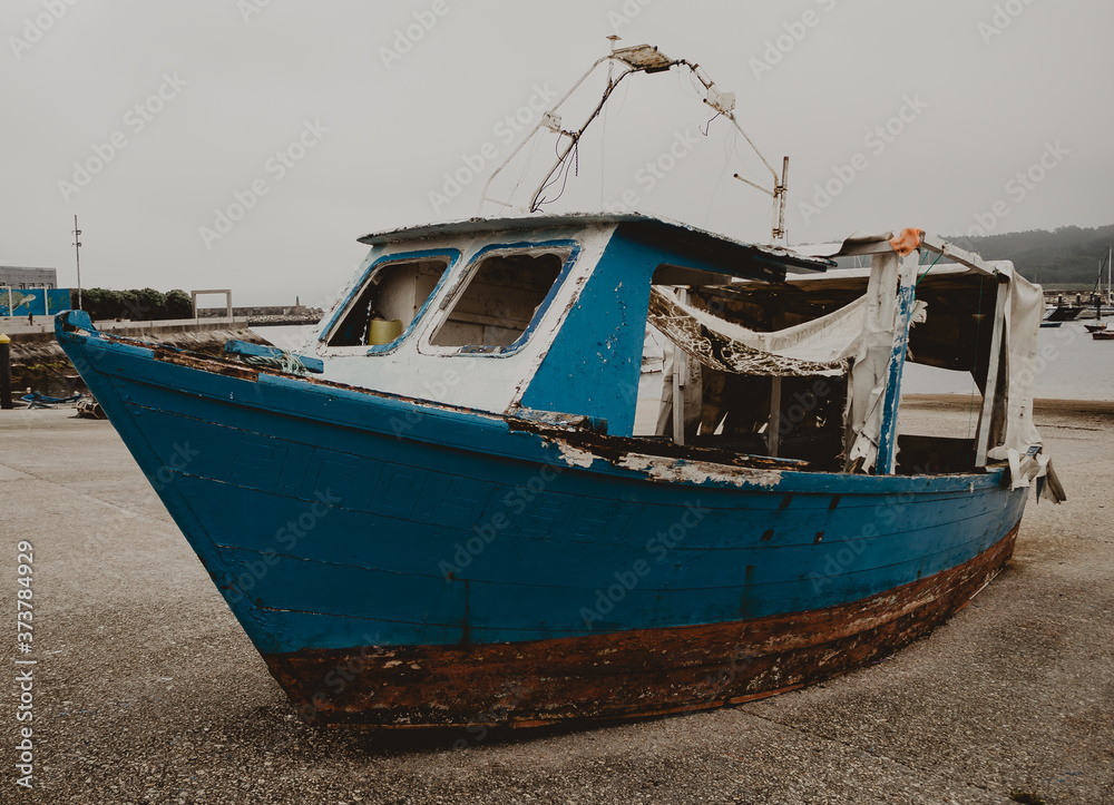 Blue fishing boat abandoned on the dock. Abandonment and deterioration concept