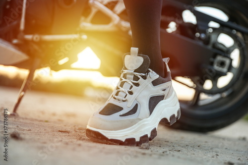 sneakers on female legs on the background of motorcycle close up