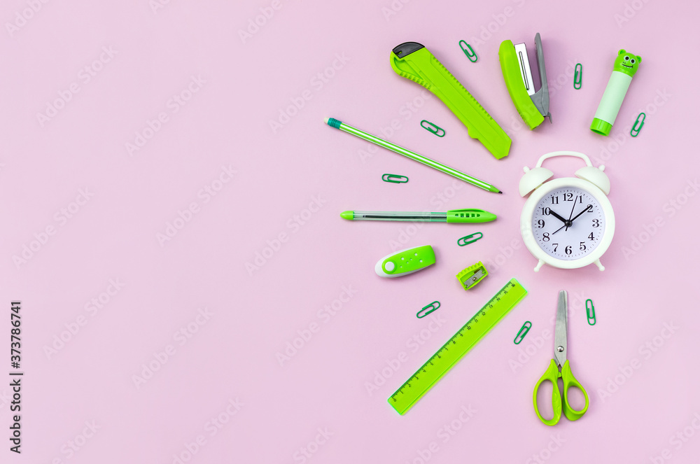 White alarm clock surrounded by stationery on pink background. Time for learning. Top view, flat lay White alarm clock surrounded by stationery on pink background. Time for learning. Top view, flat lay