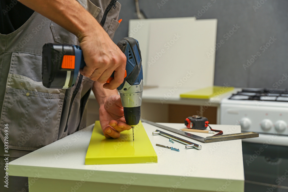 custom made wallpaper toronto digitalfurniture assembly service. employee installs a handle on a furniture door. worker drills a hole for attaching a furniture door handle