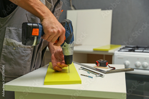 Wallpaper Mural furniture assembly service. employee installs a handle on a furniture door. worker drills a hole for attaching a furniture door handle Torontodigital.ca