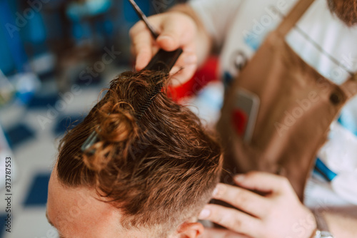 Close up of hands of a hairdresser cutting a young caucasian man's hair. Making a new hairstyle
