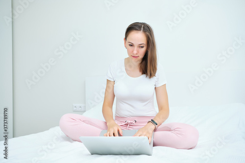 Young caucasian woman sitting on sofa and using laptop at home