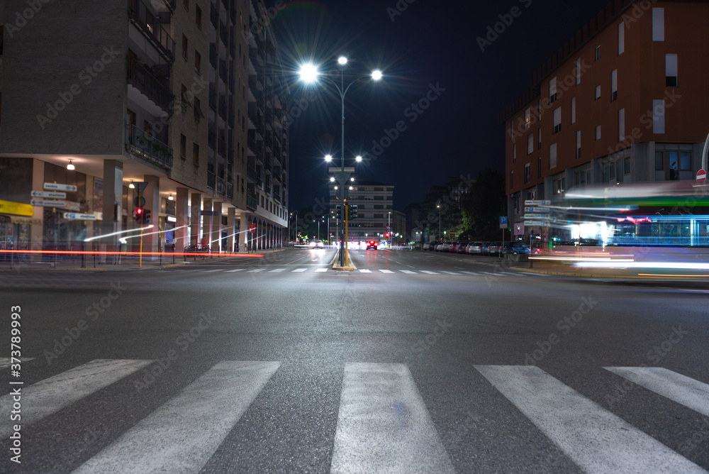 Fototapeta premium Timelapse view of traffic at an urban night intersection. Urban movement in the Italian city in the evening.