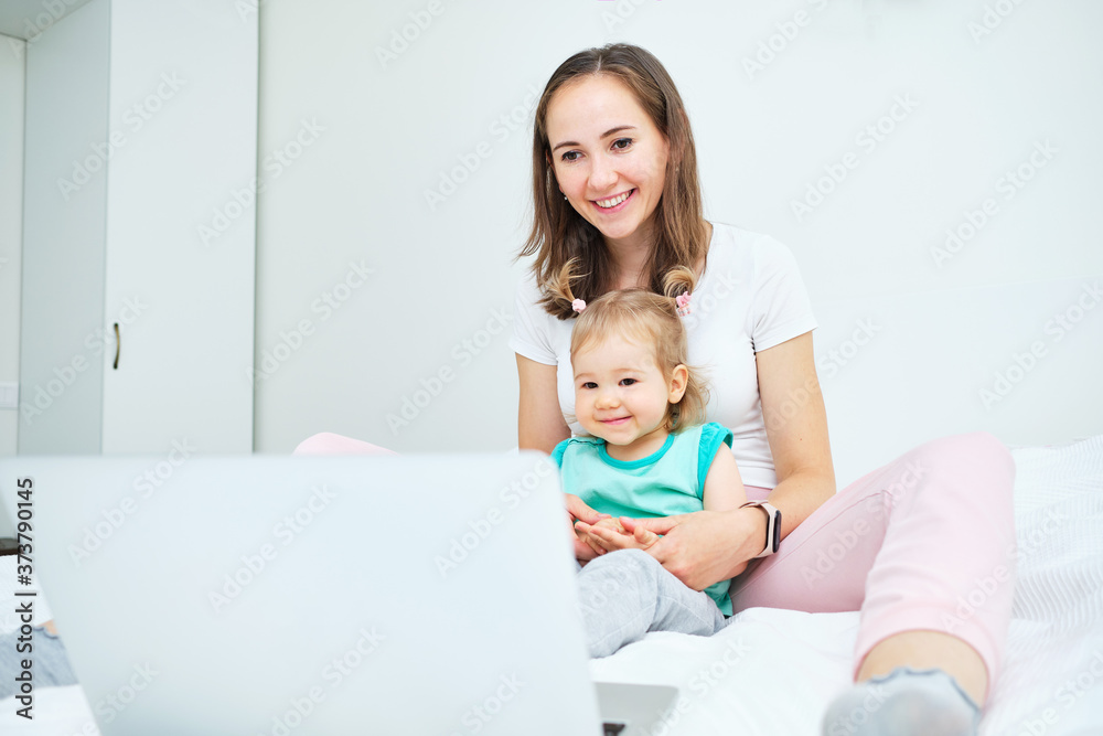 Portrait of happy caucasian child and mom sitting on sofa and watching video on laptop Portrait of happy caucasian child and mom sitting on sofa and watching video on laptop