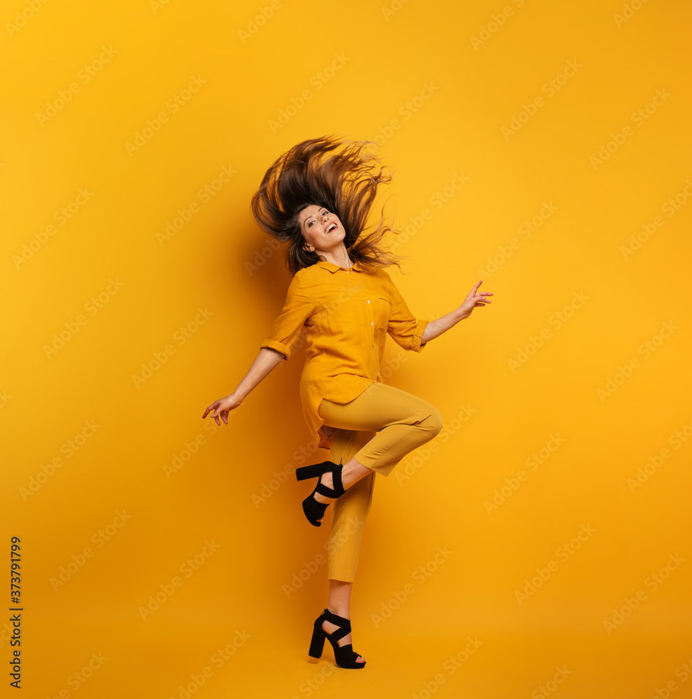 Brunette girl with a yellow clothes jumps. concept of fashion and shopping with joyful expression Brunette girl with a yellow clothes jumps. concept of fashion and shopping with joyful expression