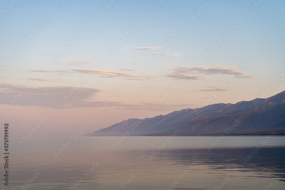 Milky air above calm baikal lake, gorgeous mountains in a mist