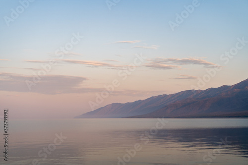 Milky air above calm baikal lake, gorgeous mountains in a mist