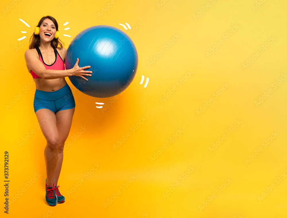 Girl with gym ball and headset is ready to start fitness activity Girl with gym ball and headset is ready to start fitness activity
