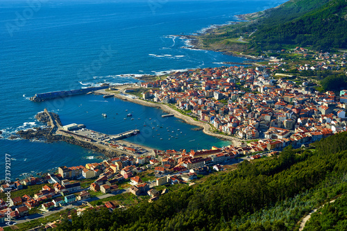 Sea port of a Guarda. Colorful buildings on the beachfront with green mountains in the background. Seascape with boats buildings and green mountain