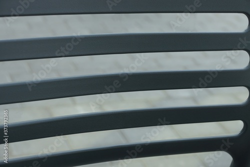 black plastic texture of striped chair back on gray background