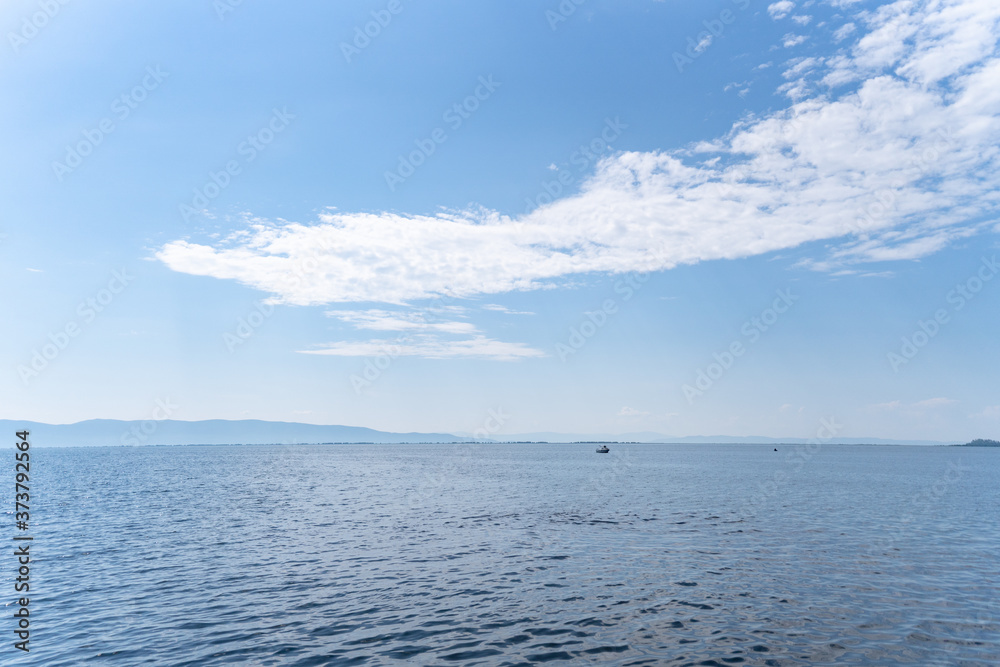Russia, Irkutsk region, Olkhon, July 2020: smooth blue water of baikal lake with clear blue sky above Russia, Irkutsk region, Olkhon, July 2020: smooth blue water of baikal lake with clear blue sky above