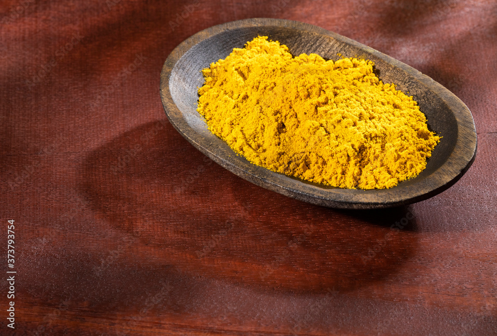 Organic curry powder in the wooden bowl - Text space Organic curry powder in the wooden bowl - Text space