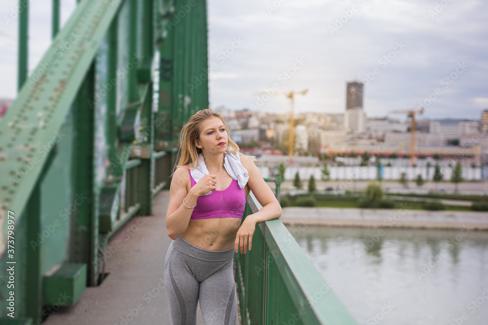 young woman standing at the bridge after workout