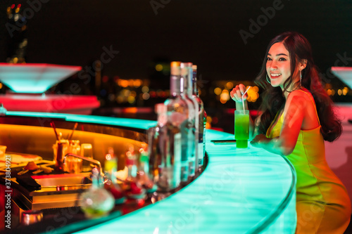 Photography happy woman on the bar counter with her cocktail at night